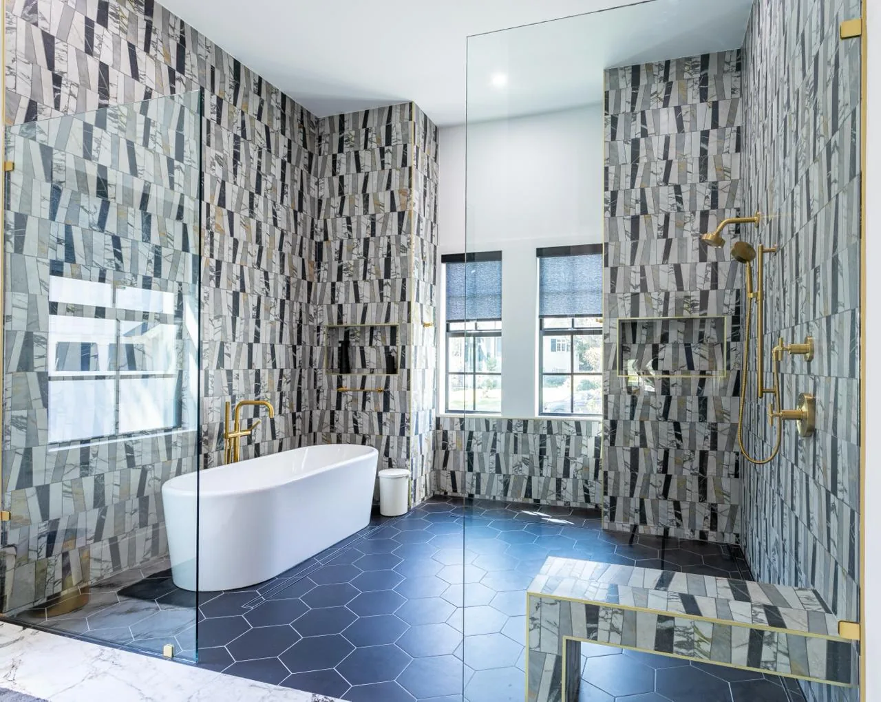Open bathroom with a walk-in glass shower, built-in bench and freestanding tub in a Bluffton home by M&H Construction & Design