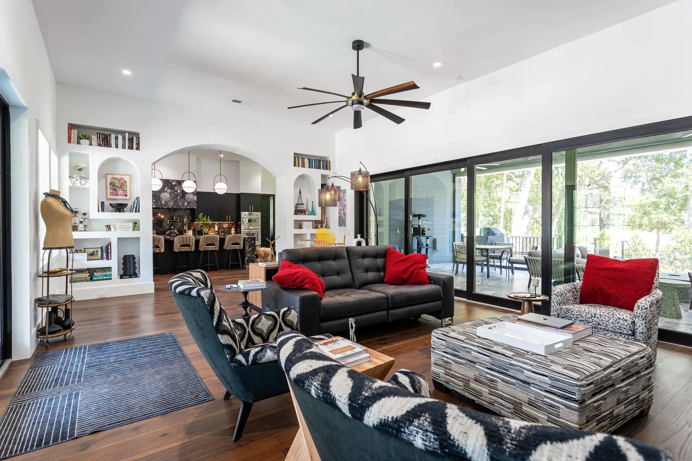 Living room with a black leather sofa, patterned armchairs, and sliding glass doors to a covered patio