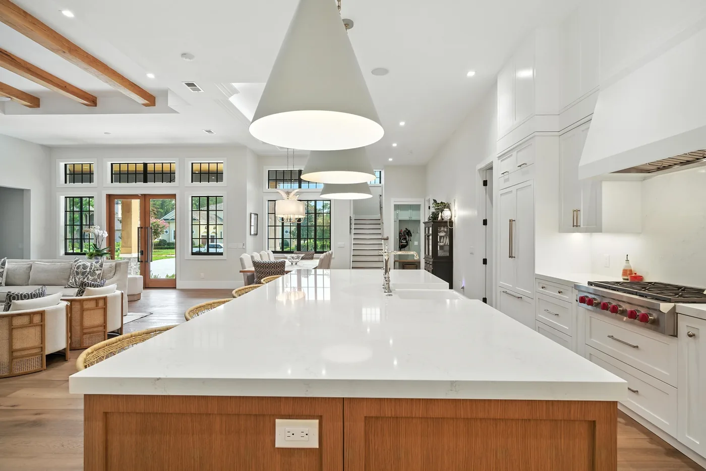 Kitchen with a large marble-topped island with a sink, white cabinetry, and a professional range by M&H Construction & Design